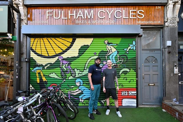 Atif Habib, owner of Fulham Cycles, stands with store mechanic Matthew King outside the store's new shutter art. Picture: H&F Council