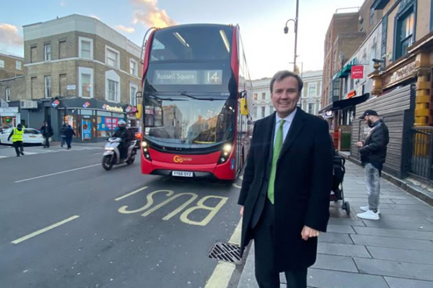 Greg Hands MP in front of a number 14 bus