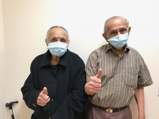 Mansukhlal and Nirmala Shah wearing face coverings and giving the thumbs-up